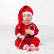 © T. Rose/peopleimages.com - Baby, portrait and cute with santa outfit for first Christmas holiday, candy cane and white background. Boy toddler, xmas and costume for festive season or celebration, innocent and adorable with hat