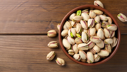 Canvas Print - Delicious pistachios in bowl on wooden table. Space for text