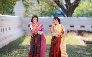 Wall Mural - Beautiful Asian woman wearing Thai dress traditional pose happiness to playing splash water during Songkran festival is funny festival traditional holiday in Thailand .