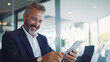 © UniqGraphicX - Businessman using tablet computer in office smiling and happy. Middle Aged Businessman wearing a Suit showing positivity, growth, and success.