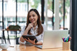 © Songsak C - Portrait of an Asian young business Female working on a laptop computer in her workstation. Business people employee freelance online report marketing e-commerce telemarketing concept.