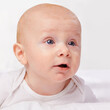 © T. Rose/peopleimages.com - Newborn, baby and blue eyes with laying on bed for curiosity, development and growth in bedroom at house. Adorable, child and cute infant with vest in home to relax, observe and wonder for knowledge