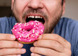 Man eats pink coloured doughnut closeup mouth.