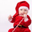 © T. Rose/peopleimages.com - Baby, portrait and studio with santa costume for first Christmas holiday, candy cane and white background. Boy toddler, xmas and outfit for festive season or celebration, innocent and adorable in hat