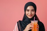 Fototapeta Londyn - Photo beautiful indonesian hijab young woman Holding Drink at copy space isolated over pink background. ads raw material