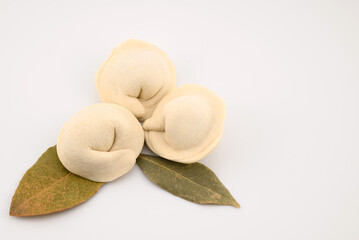 homemade raw dumplings and bay leaf, close-up top view, on a white background