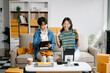 © Nuttapong punna - Fashion blogger concept, Two Asian women selling clothes on video streaming.Startup small business SME, using smartphone or tablet taking receive and checking.