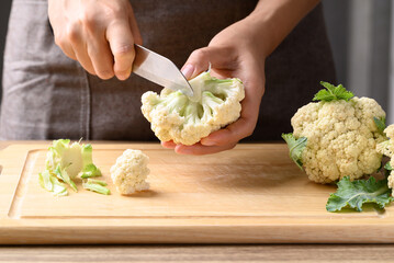Wall Mural - Hand holding knife and cutting organic cauliflower, Homemade cooking