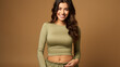 Smiling young woman in olive green crop top, fashionably casual with a confident pose.