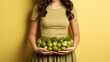 Woman in olive top holding a variety of green vegetables, promoting healthy eating and nutrition.