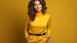 Stylish woman in a vibrant yellow turtleneck and high-waisted trousers with a sleek black belt, exuding confidence.