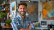 Confident and happy man with a beard and plaid shirt posing with arms crossed in a creative workspace