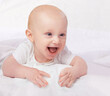 © T. Rose/peopleimages.com - Newborn, baby and smile with laying on bed for playful, fun and laugh in bedroom at house. Adorable, cute infant and relax with happiness in home child development, wellness and excited in nursery
