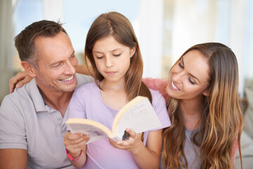 Poster - Father, girl and mom with book on sofa for hug, care or connection in family home for reading. Dad, mother and daughter on couch together with teaching, education or embrace for storytelling in house