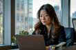 © Robert - Asian business woman working on a laptop in a professional office.