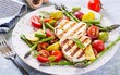 Grilled halloumi cheese salad with tomatoes and asparagus on plate on light background