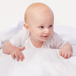 © T. Rose/peopleimages.com - Baby, bed and cute smile with laying for happiness, development and growth in bedroom on blanket. Child, adorable and happy infant in home to relax, curious and wonder for knowledge at house