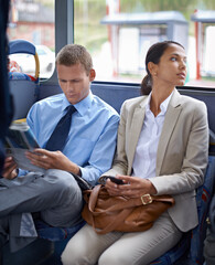 Canvas Print - Business people, man and woman on bus for public transport, newspaper and smartphone for urban commute. Professional, colleagues and coworkers in transit or traveling to work in formal clothes