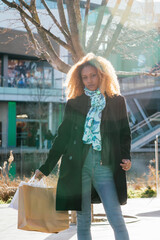 Canvas Print - Young black girl holding shopping bags looking at camera outside a shopping center