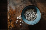 Fototapeta Mapy - Overhead view of a bowl of sunflower seeds placed on a rustic wooden table