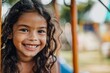 Young Close up Hispanic girl playing on a climbing frame in a playground smiling to camera