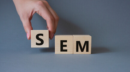 Wall Mural - SEM - Search Engine Marketing symbol. Wooden cubes with words SEM. Businessman hand. Beautiful grey background. Business and SEM concept. Copy space.