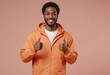 © natakot - A smiling man in an orange jacket shows thumbs up. His casual look and friendly demeanor suggest approachability and positivity.