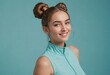 A cheerful woman in a sleeveless top smiles brightly. Her playful hair buns and the turquoise backdrop add a fun, youthful vibe.