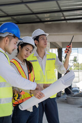 Wall Mural - Civil engineer teams meeting working together wear worker helmets hardhat on construction site in modern city. Foreman industry project manager engineer teamwork. Asian industry professional team