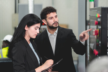 A Professional female engineer and Male CEO are working on PLC Control panel CNC machine. Expertise and technician repairman is maintenance, programming, and improve the automatic innovation machinery