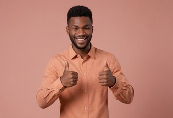 Wall Mural - A friendly young African descent man with double thumbs up, peach background. His expression is one of happiness and assurance.