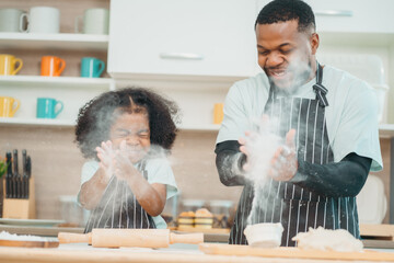 Wall Mural - happy child family with father or mother cooking fun together for bakery bread meal in kitchen, young African little kid daughter girl and parent in love childhood lifestyle at home for food homemade