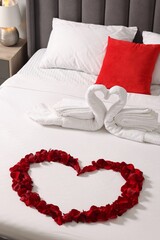 Canvas Print - Honeymoon. Swans made with towels and heart of beautiful rose petals on bed in room