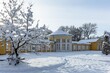 Marienbad, Czech Republic - December 4 2023: Yellow and white building of Ferdinand Spring pavilion during winter time and trees covered with snow. Sunny evening with shadows.