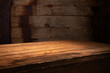 Old wood table with blurred concrete block wall in dark room background. High quality photo