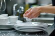 A woman in the kitchen washes a plate under running water
