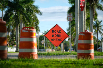 Wall Mural - Road work ahead sign and barrier cones on street site as warning to cars about construction and utility works