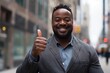 © Adriana - Happy handsome smiling professional black businessman, happy confident positive male entrepreneur standing outdoor on street thumbs up, looking at camera,