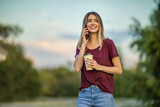 Fototapeta  - Young woman chatting outdoors with her smartphone