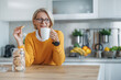 © ivanko80 - Elderly woman enjoying cookies and coffee in kitchen