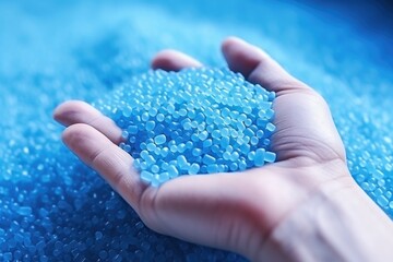 A hand hold or touching plastic pellets   plastic polymer dye granules color clear blue