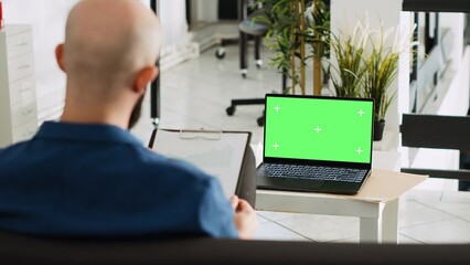 Poster - Company worker with greenscreen display reviewing documents, looking at chromakey blank template in open space. Businessman using laptop and analytics for successful research plan.