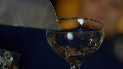 Poster - Close up of bartender putting large cubes of ice nto the empty vintage glass. Media. Preparations for the cocktail at a bar.