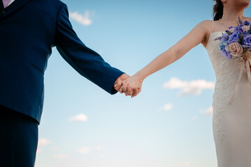 bride and groom holding hands, wedding day, blue sky