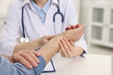 Fototapeta Panele - Arthritis symptoms. Doctor examining patient's wrist in hospital, closeup