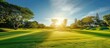 The vibrant green grass of the golf course is illuminated by the suns rays, creating a stunning and picturesque scene. The clear sky and gentle breeze make it an ideal day for golfing.