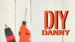 Diy danny text in orange letters with drill and electric screwdriver on white wooden boards