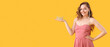 Young woman in prom dress with crown on yellow background