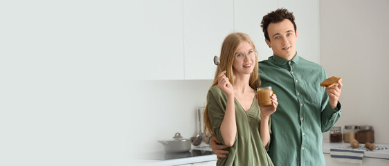 Sticker - Young woman holding jar of nut butter and handsome man with toast in kitchen