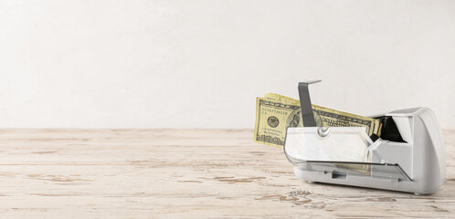 Sticker - Dollars in currency counting machine on wooden table against light background